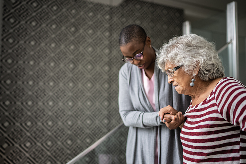 nurse in street clothes walking senior woman down stairs nurse in street clothes walking senior woman down stairs