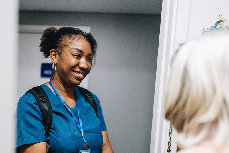nurse standing at door with senior woman