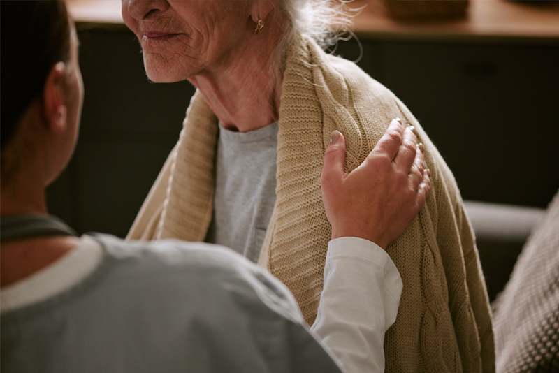 nurses hand on senior woman shoulder